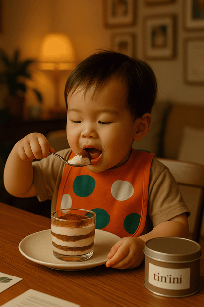 Child eating dessert with a spoon at a table, wearing an orange bib with green polka dots.